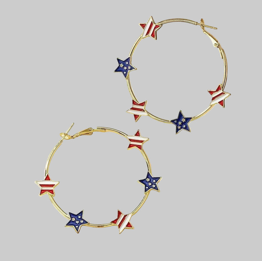 Gold hoop earrings with red, white, and blue star accents on a gray background