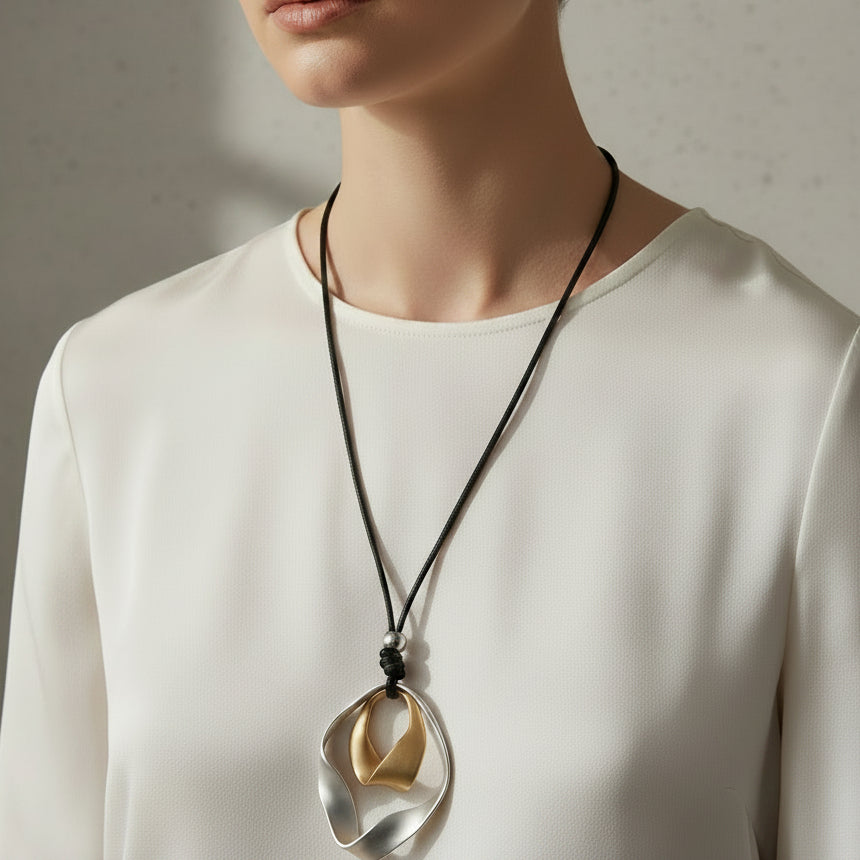 Two necklaces with unique pendants on a textured surface.