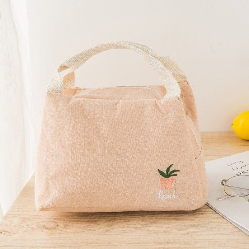 Insulated lunch bag with cotton and linen material, featuring thick aluminum foil interior and zipper closure on a wooden table.