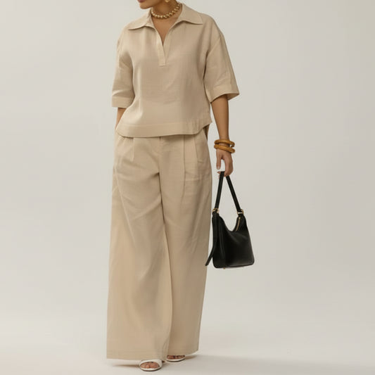 Woman in beige outfit holding a matching handbag against a neutral background
