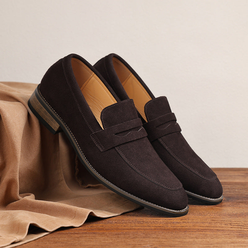 Men's dark brown suede leather penny loafer sitting elegantly on a light cream travertine stone backdrop inside a luxury studio.