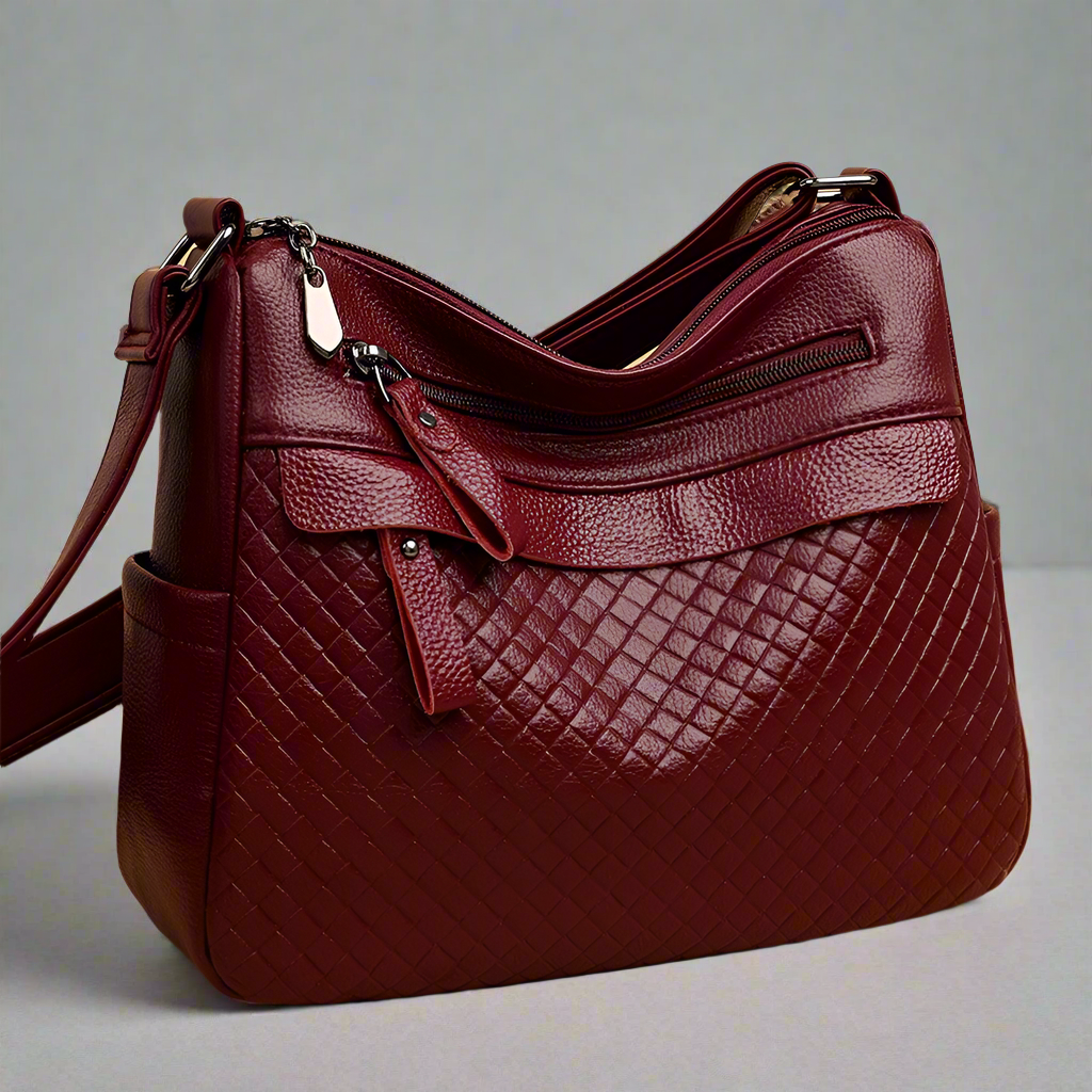 Red leather handbag with a textured pattern on a light gray background