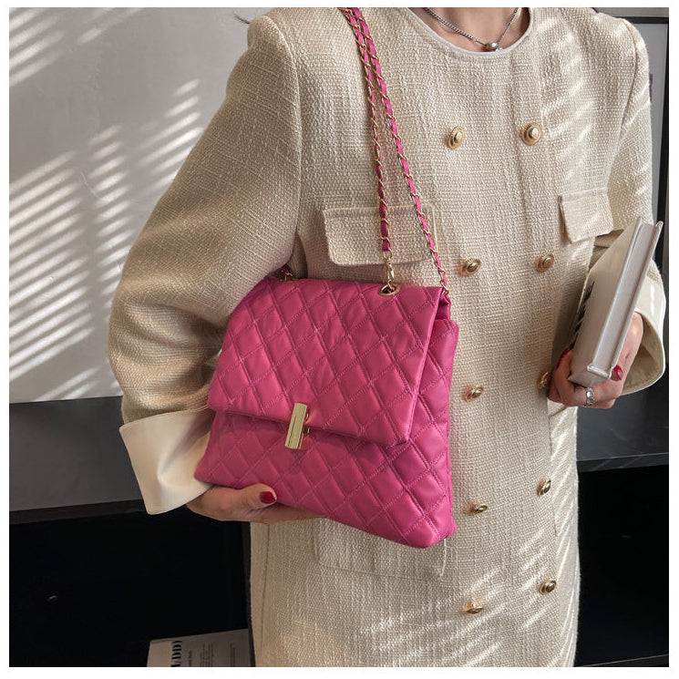 Pink quilted leather messenger bag with a gold chain strap.
