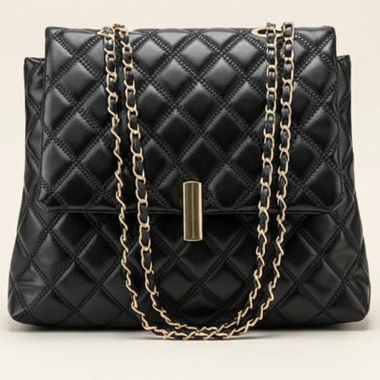Black quilted leather handbag with a gold-tone chain strap and a central gold clasp, photographed against a light beige background.