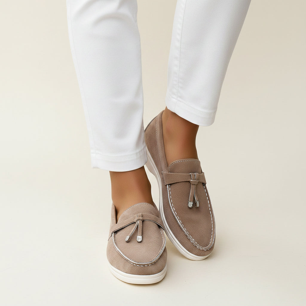 Model wearing taupe women's French tassel loafers styled with black cropped pants