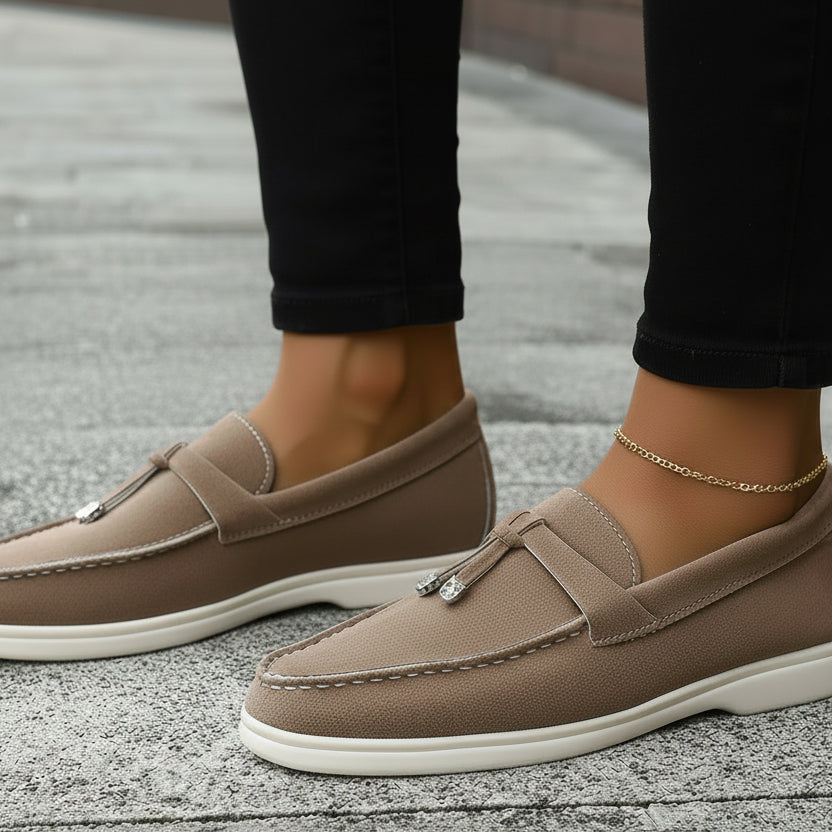 Brown loafers worn with denim jeans on a pavement background