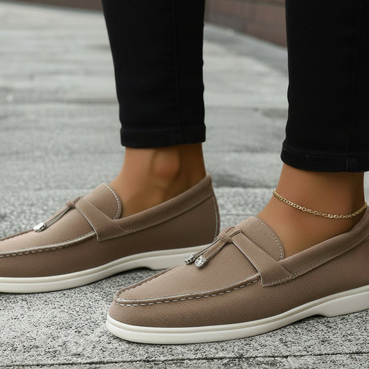 Brown loafers worn with denim jeans on a pavement background