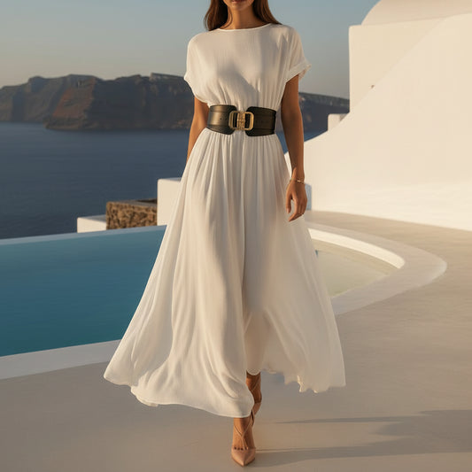 Elegant woman wearing a flowing white resort dress walking through a Mediterranean-inspired courtyard with timeless luxury style.