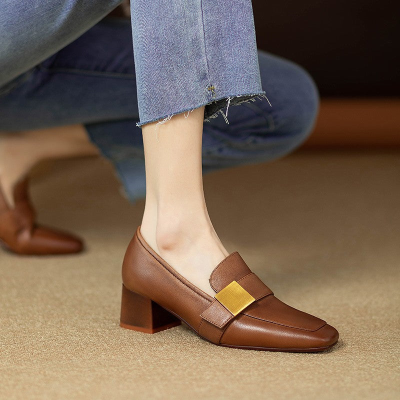 Brown loafer shoe with gold buckle worn by a person in jeans.