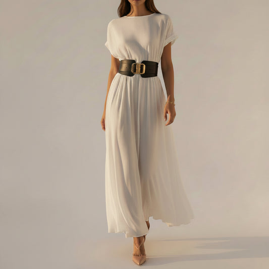 Elegant woman wearing a flowing white resort dress walking through a Mediterranean-inspired courtyard with timeless luxury style.