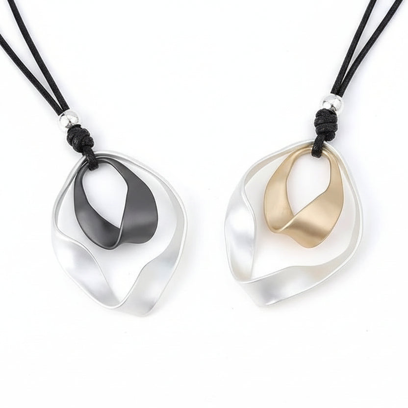Two necklaces with unique pendants on a textured surface.