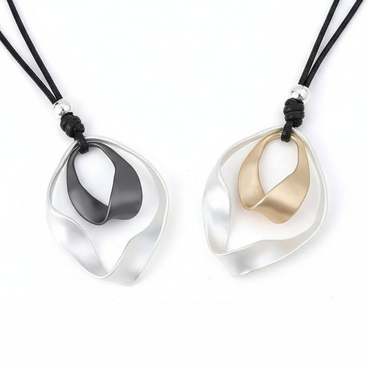Two necklaces with unique pendants on a textured surface.