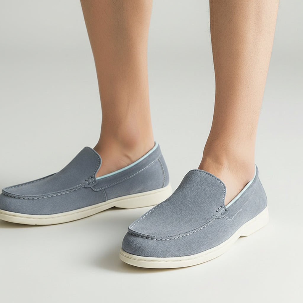 Person holding a pair of gray loafers with a plain background