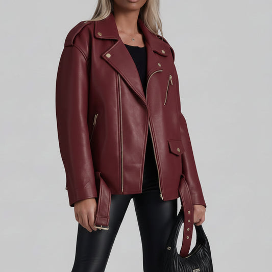 A model wearing a premium oversized dark cherry burgundy faux leather moto biker jacket with silver hardware, styled on a chic outdoor city street.